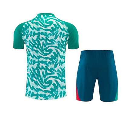Conjunto de treino Velukz com padrão abstrato verde e branco, calções azuis com detalhes vermelhos e verdes.